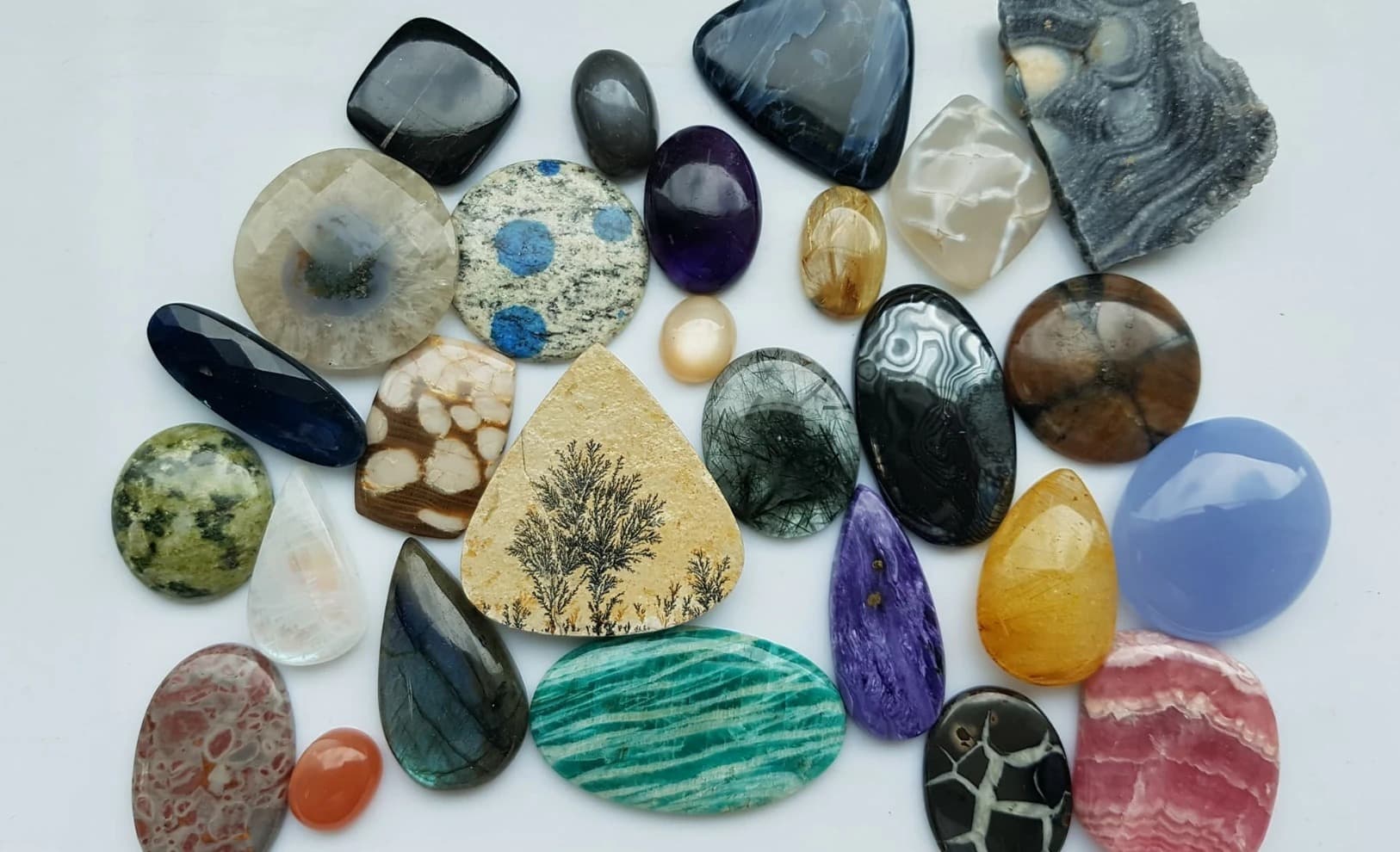 A curated flatlay of natural coloured gemstone cabochons